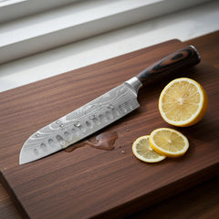 Damascus chef knife slicing lemon on walnut cutting board — view 2