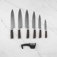 Six Damascus blades and charcoal sharpener arranged on marble — view 3